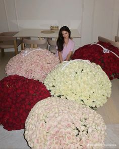 a woman sitting on the floor surrounded by large bouquets of white and red roses