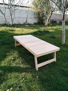 a wooden table sitting in the grass next to a tree