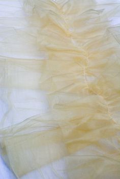 a white dress with yellow ruffles on the bottom is laying on a bed