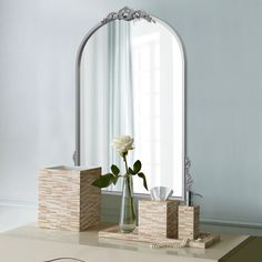 a vase with a flower in it sitting on a table next to a mirror and other items