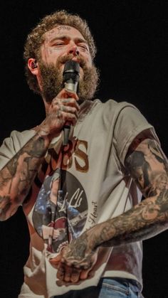 a bearded man with tattoos holding a microphone