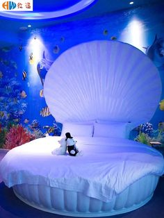 a large bed with an ocean theme on the wall and under it is a teddy bear