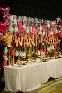 a table topped with lots of desserts and balloons next to a wall covered in streamers