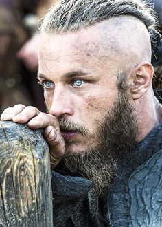 a close up of a person with a goatee and blue eyes holding a tire