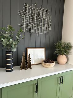 some plants are sitting on top of a white counter in front of a black wall