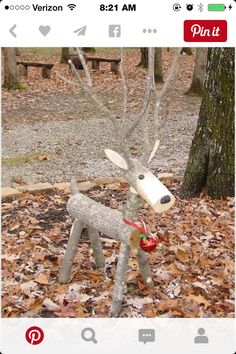 a statue of a deer is in the middle of leaves on the ground next to a tree