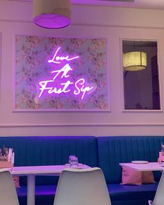 the interior of a restaurant with blue booths and purple lighting on the wall above it