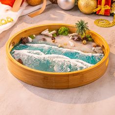 a wooden tray with an ocean scene in the center and christmas decorations on the other side