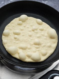 an uncooked pancake sitting on top of a stove next to a frying pan