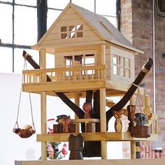 two figurines are sitting on top of a wooden structure with a tree house in the background