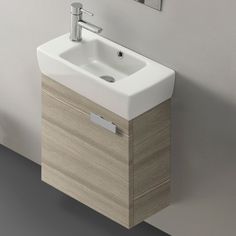 a white sink sitting next to a wall mounted faucet in a bathroom under a mirror