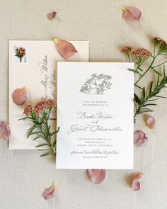 the wedding stationery is laid out on top of each other with pink flowers and greenery