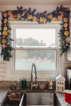 a kitchen sink sitting under a window covered in christmas decorations