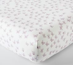 a close up of a bed sheet with purple flowers on the cover and white sheets