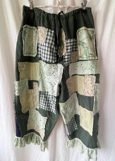 These plus-sized upcycled green cotton pants are decorated with an abundance of patches such as floral, checked cotton, silk, denim, botanical, and lace. The lace and patches have been dyed a very light green with natural plant dye. They are a women's size 18. The legs are flared starting about 11 inches from the waistband. There is some hand stitching included on the front pockets. There is extensive fraying on all of the patches and the triangle inserts on the sides of the pant legs. Here are the measurements for the upcycled pants: waistband-40 inches length-35 inches inseam-22 inches thigh circumference-30 inches hem circumference- 25 inches bottom lace circumference- 38 inches There are two buttons for an adjustable fit. When the drawstring is cinched and the second button is buttoned Upcycled Pants, Green Cotton Pants, Denim Patchwork Jeans, Patchwork Pants, Chic Pants, Clothes Diy, Patchwork Jeans, Plus Sized, The Triangle