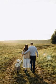 a man and woman walking down a dirt road with a baby in a stroller