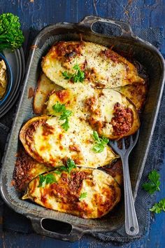 baked stuffed potatoes with meat sauce and parmesan cheese in a baking dish on a blue wooden table