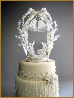 a wedding cake with white frosting and flowers on top is decorated with a bell