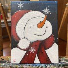 a painting of a snowman wearing a santa hat and scarf on a easel