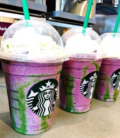 three starbucks drinks with green straws and whipped cream