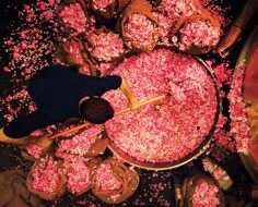 a man standing in front of a large pot filled with pink sprinkles