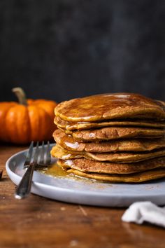 a stack of pancakes sitting on top of a plate next to a knife and fork