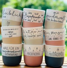 a stack of coffee cups with writing on them sitting on top of a wooden table