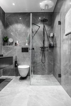 a modern bathroom with grey marble walls and flooring, including a walk in shower