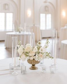 the centerpieces are arranged in glass vases and candles on the round table