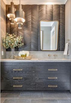 a bathroom vanity with marble counter top and gold accents on the mirror above it is decorated with flowers