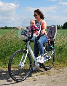 a woman is sitting on a bike with a baby in her seat and she is looking at the camera