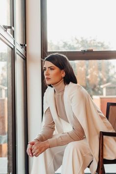 a woman sitting on a chair in front of a window