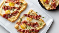 three small pizzas with bacon and eggs on them sitting on a white platter