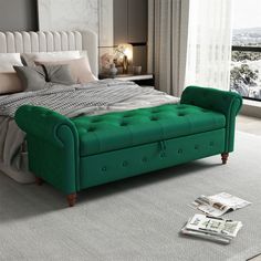 a green tufted bed with pillows and blankets on it in a bedroom next to a window