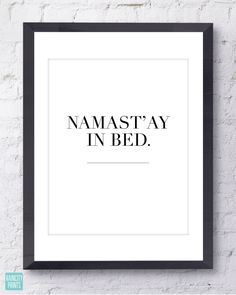 the words namastay in bed printed on a white brick wall above a black frame