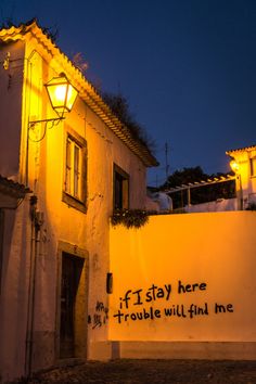 a white building with writing on the side and lights above it that says, if i stay here trouble will find me