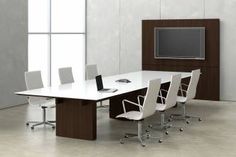 an empty conference table with white chairs and a flat screen tv mounted on the wall