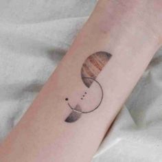 a woman's arm with a small saturn tattoo on it