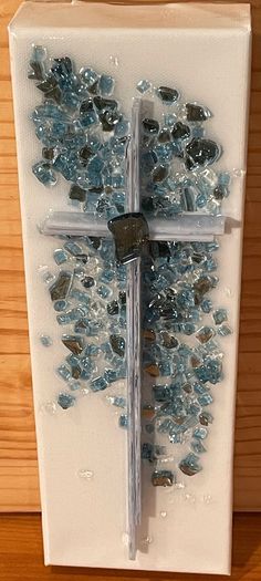 a cross made out of glass on top of a wooden table next to a wall