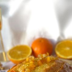 a loaf of bread with oranges and wine in the background