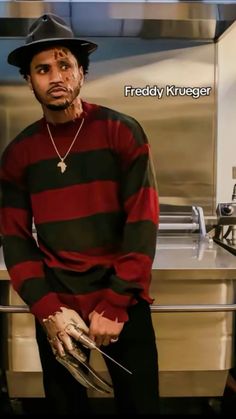 a man wearing a black and red striped shirt standing in front of a kitchen counter