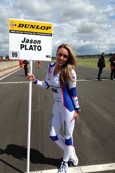 a woman standing next to a sign on top of a tarmac