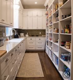 a kitchen filled with lots of white cupboards and shelves next to a counter top