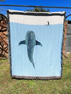 a blue whale quilt hanging on a clothes line in the grass with a person standing next to it