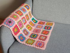 a crocheted blanket is sitting on the arm of a couch