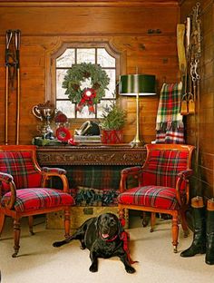 a dog laying on the floor next to two chairs in a room with wood paneled walls