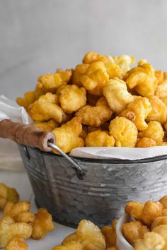 a metal bucket filled with fried food next to two small bowls full of tater tots