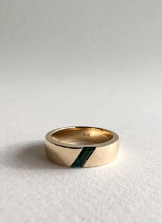 This 6mm wide men's wedding band features a stunning Parallelogram emerald stone sitting on an angle, with custom engraving on the inside of the band. Set in yellow gold Emerald Male Wedding Band, Men’s Gemstone Wedding Ring, Male Wedding Bands Emerald, Men’s Emerald Engagement Rings, Cool Men Wedding Band, Mens Wedding Bands With Emeralds, Men’s Wedding Bands With Stones, Men Engagement Ring Unique, Men Wedding Rings Unique