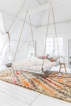 a white bedroom with a swing bed and rug