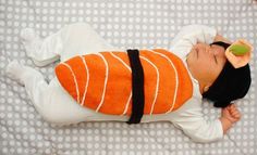 a baby is sleeping on a bed wearing an orange and black outfit